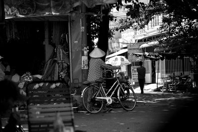 Rear view of woman sitting on street in city