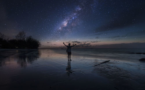 Man standing at beach against sky at night