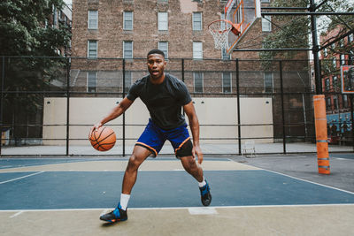 Young man practicing basketball in court