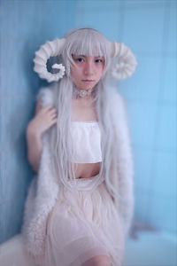 Portrait of a girl standing against white wall