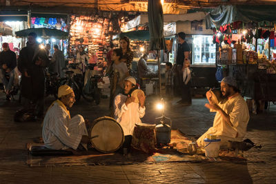 People sitting at market stall at night