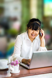 Young woman using mobile phone on table