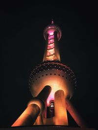 Midsection of person holding illuminated tower against sky at night