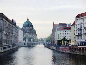 View of canal by city against sky