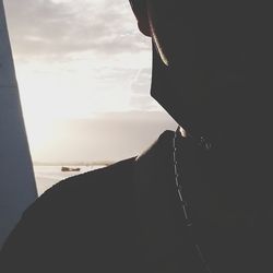 Close-up portrait of silhouette man against sky seen through window