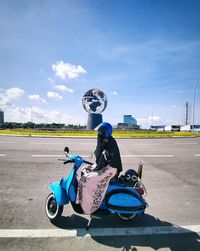 Man riding motorcycle on road against blue sky