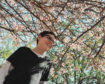 Low angle portrait of young woman against tree