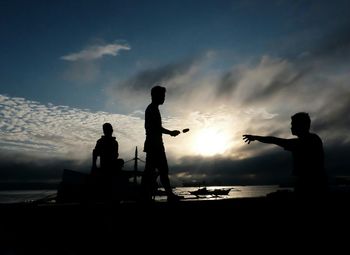 Silhouette man in sea at sunset