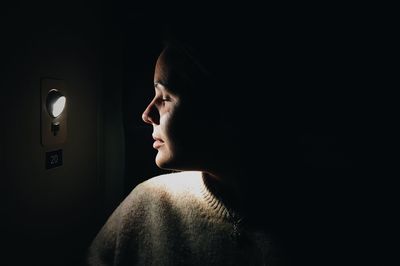 Side view of young woman against black background