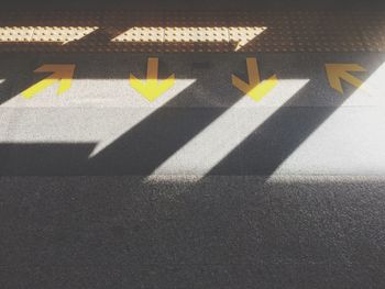 Close-up of arrow sign on tiled floor