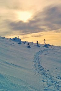 People on snow covered land against sky during sunset