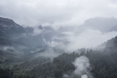 Scenic view of mountain against dramatic sky during foggy weather