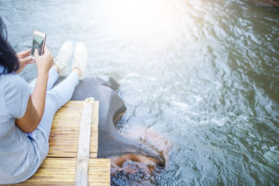 High angle view of woman sitting on pier at lake