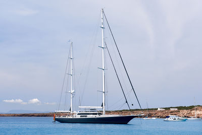 Sailboat on sea against cloudy sky