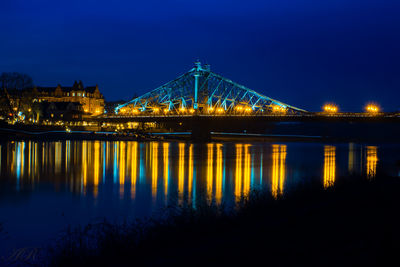 Illuminated bridge over river at night