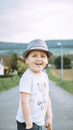 Portrait of boy standing on road against sky