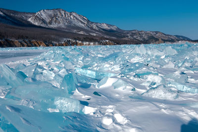 Pieces of crystal clear lake ice with mountains in background