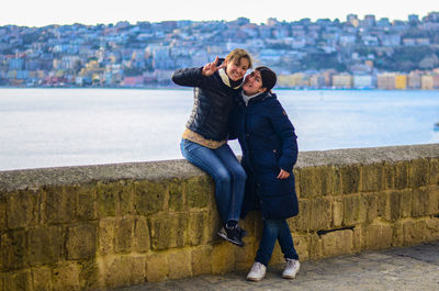 Two young smiling women on the background of the city at sunset. blue sea in the background