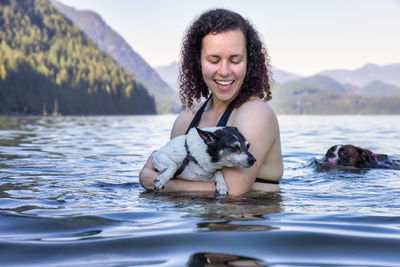 Portrait of smiling woman with dog in water