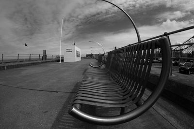 Empty footpath by railing in city against sky