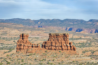 Rock formations on landscape against cloudy sky