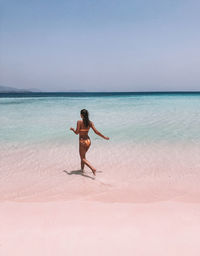 Woman running in sea against clear sky