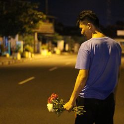 Side view of young man standing on street at night