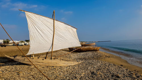 Sailboat on beach by sea against sky