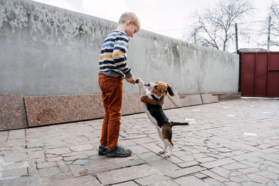 Full length of man with dog standing on footpath