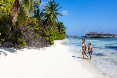 Mother and son getting out of the water on a beach in the maldives