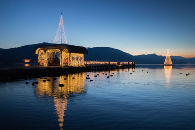 Reflection of illuminated building in lake at dusk