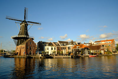 Buildings by river against sky