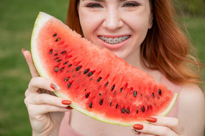 Smiling woman holding slice of watermelon