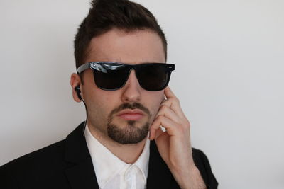 Portrait of young man wearing sunglasses against gray background
