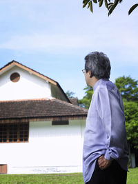 Side view of man standing against building
