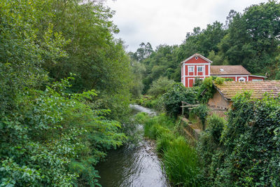 Scenic view of river amidst trees and houses against sky