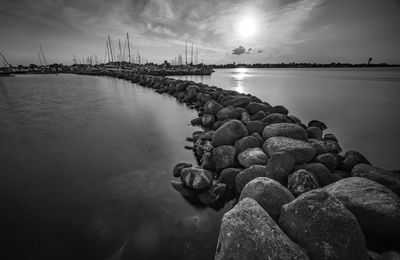 Rocks at sea shore against sky during sunset