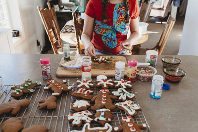 Girls hands putting sprinkles on christmas cookies