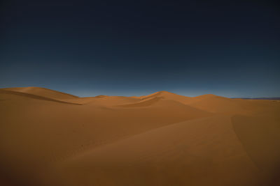 Scenic view of desert against clear blue sky