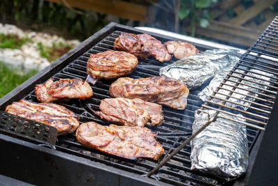 Pieces of fresh meat and fish in foil are laid out on a grill grate. barbecue cooking. 