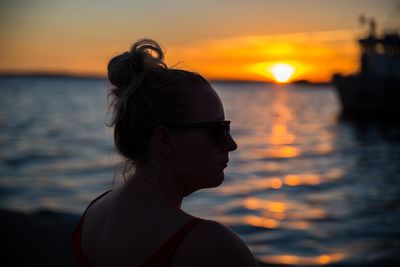 Portrait of woman in sea against sunset sky