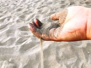 Close-up of human hand holding sand at beach