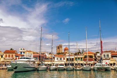 Boats moored at harbor by buildings against sky