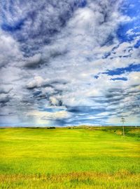 Scenic view of grassy field against cloudy sky