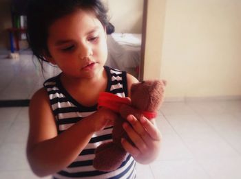 Close-up of girl playing with teddy bear at home