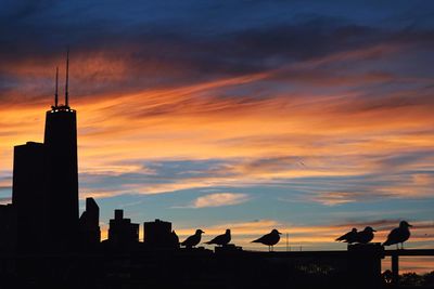 Silhouette of building against cloudy sky at sunset