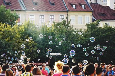 High section of crowd and bubbles against trees and building