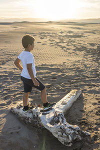 Full length of boy standing on sand at beach against sky