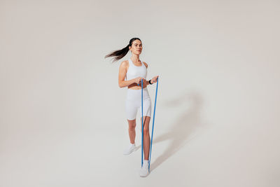 Portrait of young woman standing against white background