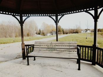 Empty benches on landscape against sky